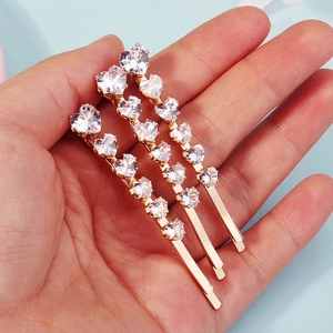 Close-up of three gold-plated hairpins with sparkling crystal heart-shaped zircons