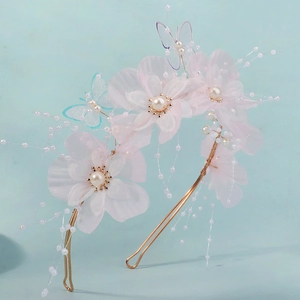 Detailed macro view of pink gauze flowers, pearls, and mesh butterfly on a bridal headband