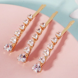 Detailed macro view of three golden hair clips with sparkling heart-shaped zircon stones