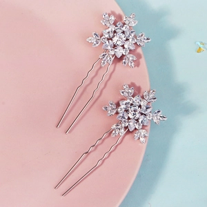Detail of silver snowflake U-shaped hair pins with sparkling crystals on a pink tray