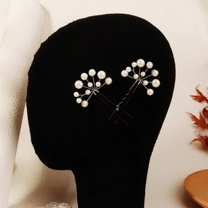 Detailed view of handmade pearl hair pins with U-shaped design on a styling head
