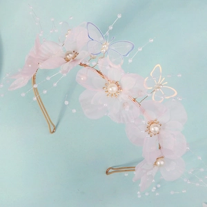 Detail of pink tulle flower headband with pearls, mesh butterfly and golden metal wings