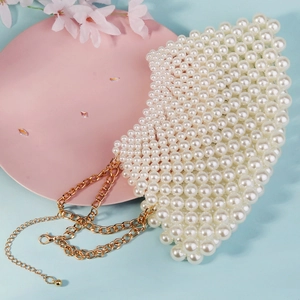 Detail of handmade woven pearl bag on pink stand with gold metal chain strap