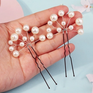 Detail of handcrafted pearl U-shaped hair pins showing intricate wire wrapping and beads