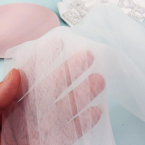 Close-up of white bridal veil mesh with pearl Bride lettering accessory for weddings