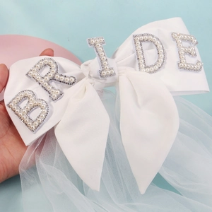 Close-up of white satin bow with pearl BRIDE lettering and layered bridal tulle veil