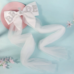 White bridal bow veil with pearls and BRIDE lettering on a soft pastel background