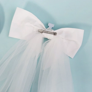 Detail of white satin bow bridal veil with pearl accents and metal hair clip back