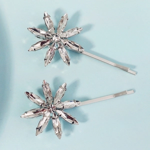Elegant silver snowflake hair clips with sparkling crystals on a light blue background