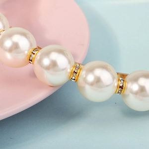 Detailed close-up of large pearls and gold diamond-encrusted rings on the headband