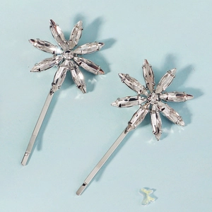Close-up of sparkling rhinestone flower hair clips on a clean light blue background