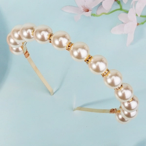 Detailed view of large white pearls and gold metal spacers with tiny diamonds on a headband