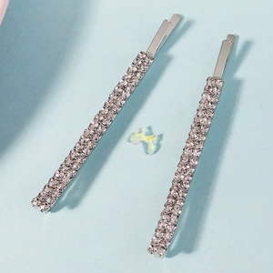 Detalle de pinzas para el cabello plateadas con diamantes sobre fondo azul claro y mariposa