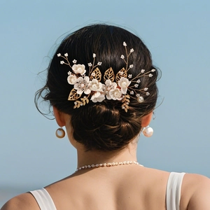 Detailed back view of a bride wearing a white floral hair comb with pearls and gold leaves