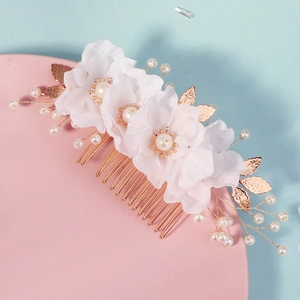 Detail of handmade bridal hair comb featuring white fabric flowers and golden leaf accents