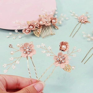 Close-up of handmade bridal hair comb set with pink flowers, pearls and golden wire branches