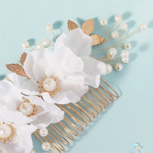 Detail of bridal hair comb with white fabric flowers, golden leaves, and pearls