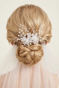 Detailed close-up of bridal hair comb with crystal flowers and pearls in a wedding hairstyle
