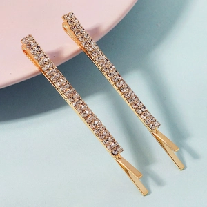 Detalle de dos pasadores dorados con brillantes cristales blancos para el pelo