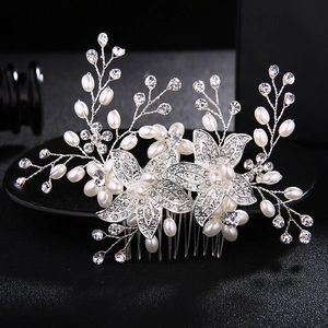 Silver bridal hair comb with crystal flowers and white pearls on a black background