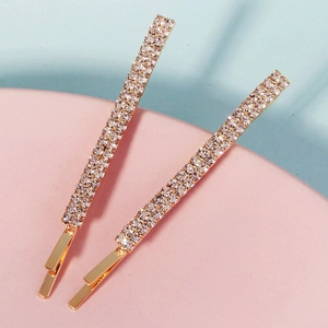 Detalle de dos pinzas doradas con cuatro filas de brillantes diamantes de imitación