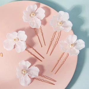 Detailed view of 5-piece white fabric flower hair pins with pearls and gold U-shaped clips
