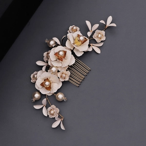 Détail d'un peigne à cheveux de mariée avec feuilles dorées et fleurs crème élégantes