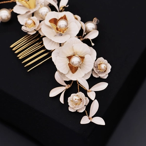 Détail du peigne à cheveux pour mariée avec des fleurs ivoire et des feuilles dorées