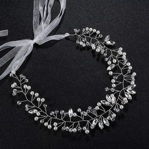 Détail d'un serre-tête de mariée avec perles blanches, cristaux et ruban en organza