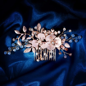 Détail d'un peigne de mariée fait main en or rose avec perles et fleurs sur soie bleue