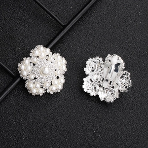 Close-up of floral clip-on earrings with micro-set pearls and shimmering rhinestones