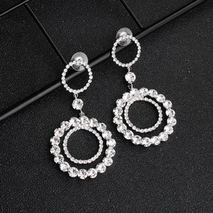 Macro shot of silver-tone double ring drop earrings with sparkling rhinestone pavé setting