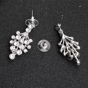 Close-up of silver dangle earrings with clustered rhinestones on black texture