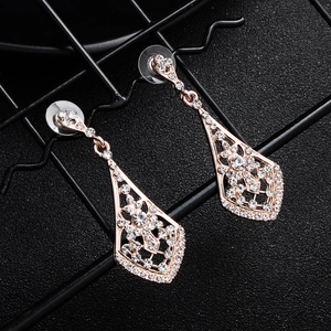 Detail of rose gold geometric drop earrings with sparkling rhinestones on black background