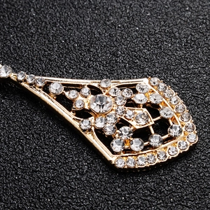 Macro detail of gold alloy rhinestone earrings with intricate hollow geometric pattern