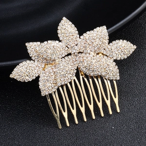 Nahaufnahme eines goldenen Brauthaarkamms mit Strass-Blumenmuster auf schwarzem Grund
