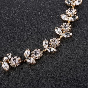 Detail of luxury bridal headband with rhinestone flowers and gold leaves on black background
