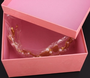 Vista dettagliata di una tiara da sposa in perle dorate in una scatola regalo rosa goffrata