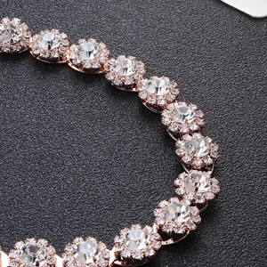 Macro shot of rose gold bridal belt with sparkling sunburst rhinestone floral clusters