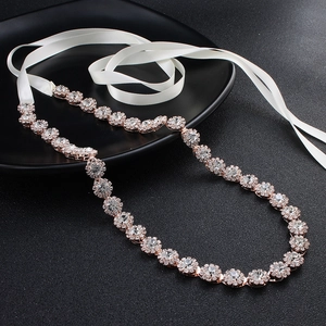 Detail view of sparkly rhinestone bridal belt with rose gold metal and white silk ribbon