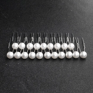 Close-up of pearl U-shaped hair pins arranged in a grid on a gray textured background