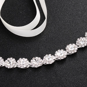 Close-up of sparkling bridal rhinestone belt with silver metal base and white satin ribbon