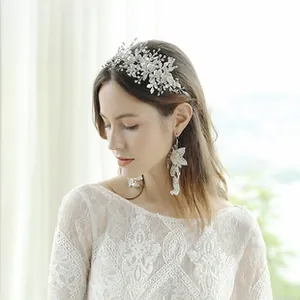 Detail of bridal headband with pearls and metal flowers on lace wedding dress
