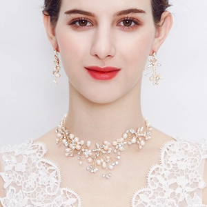Dettaglio del set di gioielli da sposa con perle bianche e grappoli di strass dorati