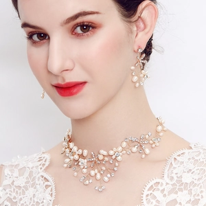 Dettaglio parure sposa con perle e strass su modella con abito in pizzo bianco elegante