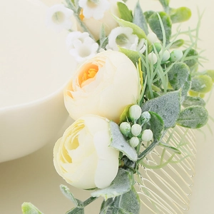 Detail of bridal hair comb with fabric roses, greenery and golden metallic teeth