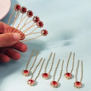 Détail d'épingles à cheveux en U dorées avec fleurs en strass rouges et cristaux
