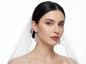Detailed view of silver bridal drop earrings with clear rhinestones on a veiled model