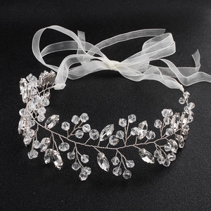 Détail macro d'un bandeau de mariée avec feuilles de cristal et ruban en organza blanc