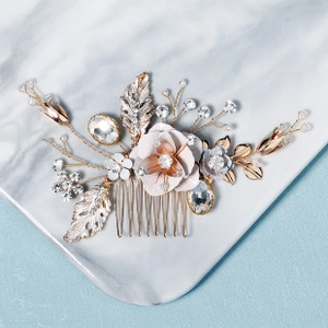 Dettaglio del pettine per capelli con fiori di seta rosa, foglie dorate, strass e perle